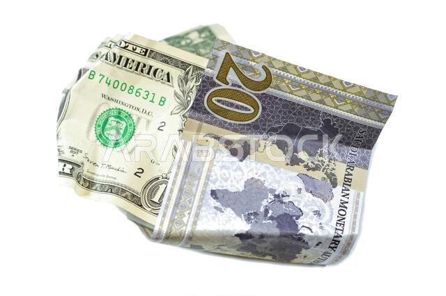 عملة سعودية مجعدة ومتكسرة من فئة 20 ريالاً سعودياً ودولار أمريكي واحد، تضخم العملة وفقدان قيمتها، مفهوم الانخفاض.