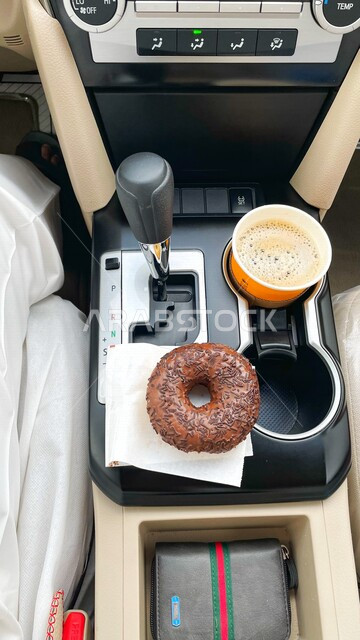 صورة مقربة لفطور صباحي مكون من القهوة الساخنة وحلوى الدونات الطرية داخل السيارة , كافيهات ومطاعم , فطور صباحي . 