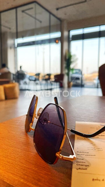 A picture inside a café in Saudi Arabia, sunglasses, men's accessories, a bill waiting for the order inside the café.