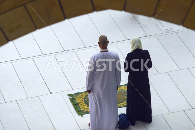 Depiction from the back of a Muslim couple praying in the mosque, getting closer to God, praying in congregation at the mosque, Islam and worship