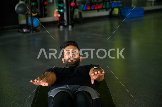 A Saudi Arabian Gulf youth doing exercises on a yoga mat, strengthening health and bodies, exercising in the gym