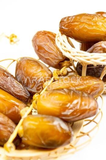 Close-up of Algerian royal dates on a wooden plate on a white background. Ramadan concept.