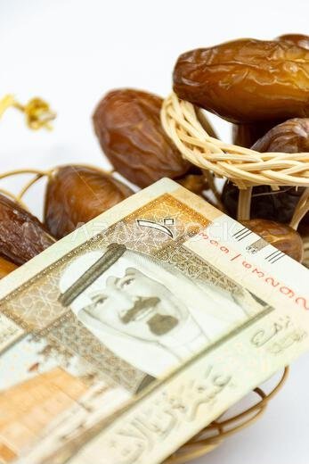 Close-up of Algerian royal dates on a wooden plate. Saudi Arabia Money Banknotes. Ramadan concept.