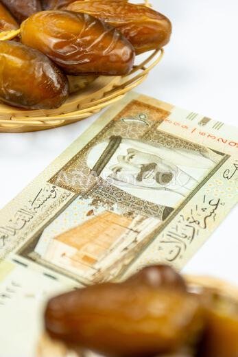 Close-up of Algerian royal dates on a wooden plate. Saudi Arabia Money Banknotes. Ramadan concept.
