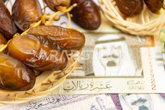 Close-up of Algerian royal dates on a wooden plate. Saudi Arabia Money Banknotes. Ramadan concept.