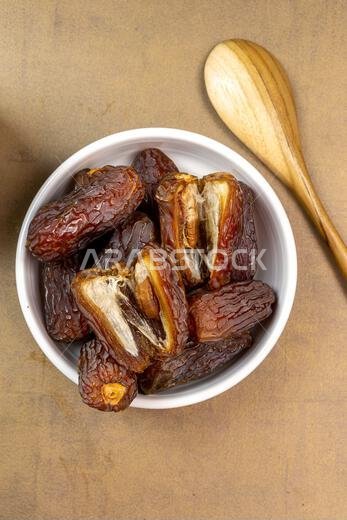 تمر مجدول عضوي خام (يُعرف باسم "كورما" في إندونيسيا). إنه أيضاً وقت إفطار رمضان. رمضان كريم. منظر علوي. مساحة لإضافة نص.