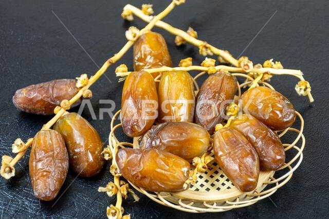 صورة مقرّبة لتمور جزائرية ملكية على طبق خشبي على خلفية سوداء. مفهوم رمضان.