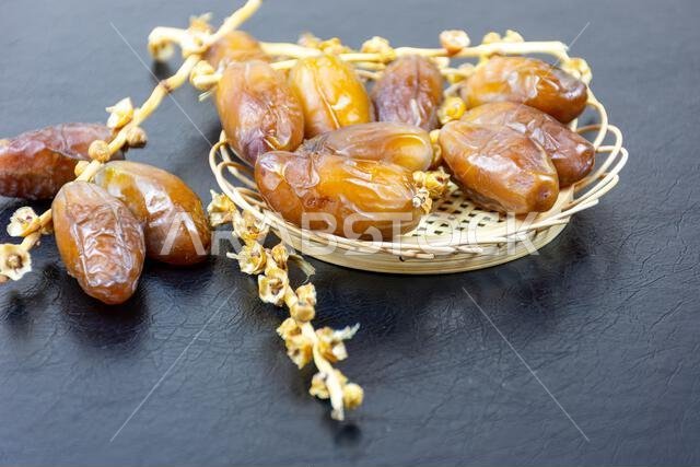 صورة مقرّبة لتمور جزائرية ملكية على طبق خشبي على خلفية سوداء. مفهوم رمضان.