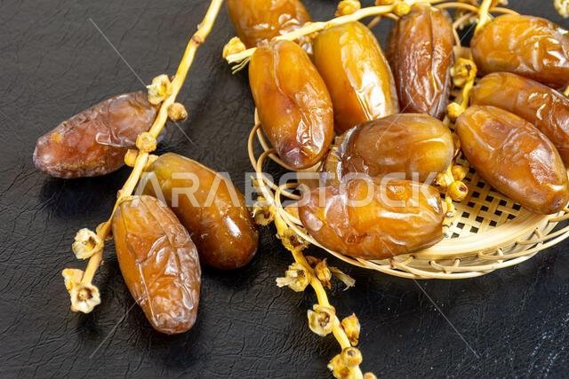 Close-up of Algerian royal dates on a wooden plate on a black background. Ramadan concept.