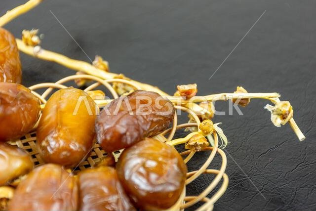 Close-up of Algerian royal dates on a wooden plate on a black background. Ramadan concept.