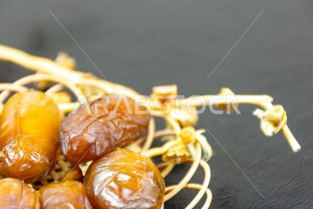 Close-up of Algerian royal dates on a wooden plate on a black background. Ramadan concept.
