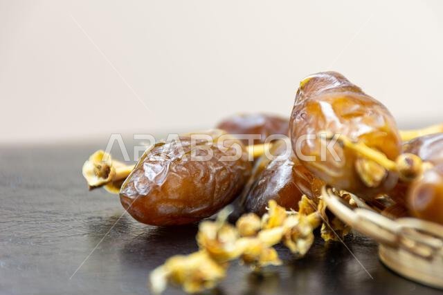 صورة مقرّبة لتمور جزائرية ملكية على طبق خشبي على خلفية سوداء. مفهوم رمضان.