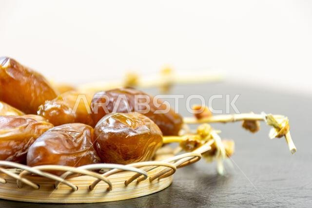 Close-up of Algerian royal dates on a wooden plate on a black background. Ramadan concept.