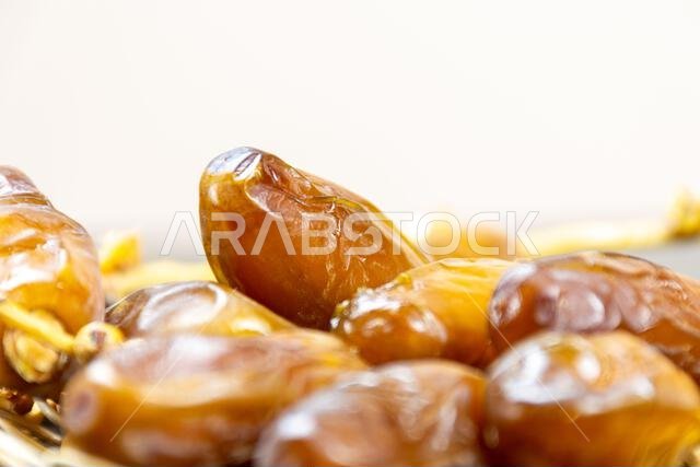 Close-up of Algerian royal dates on a wooden plate on a black background. Ramadan concept.