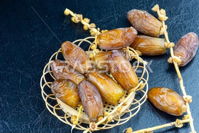 Close-up of Algerian royal dates on a wooden plate on a black background. Ramadan concept.