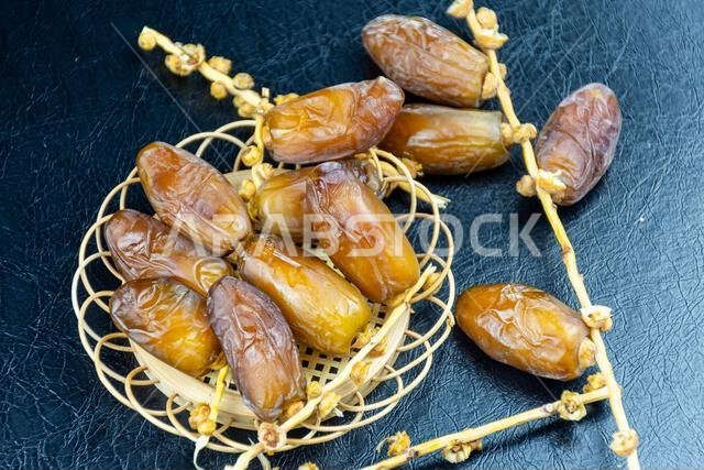 صورة مقرّبة لتمور جزائرية ملكية على طبق خشبي على خلفية سوداء. مفهوم رمضان.