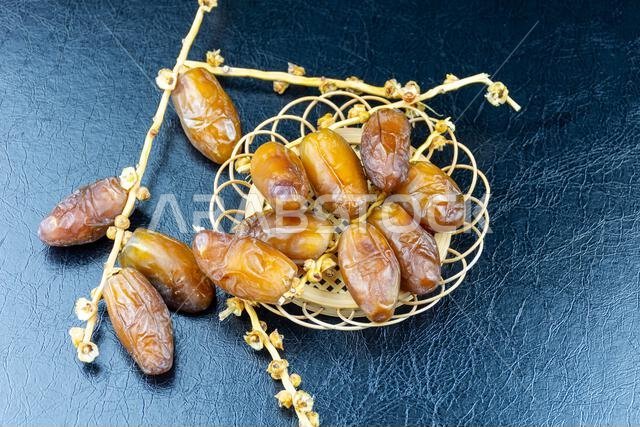 Close-up of Algerian royal dates on a wooden plate on a black background. Ramadan concept.