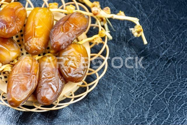 Close-up of Algerian royal dates on a wooden plate on a black background. Ramadan concept.
