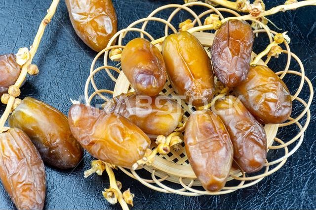 صورة مقرّبة لتمور جزائرية ملكية على طبق خشبي على خلفية سوداء. مفهوم رمضان.