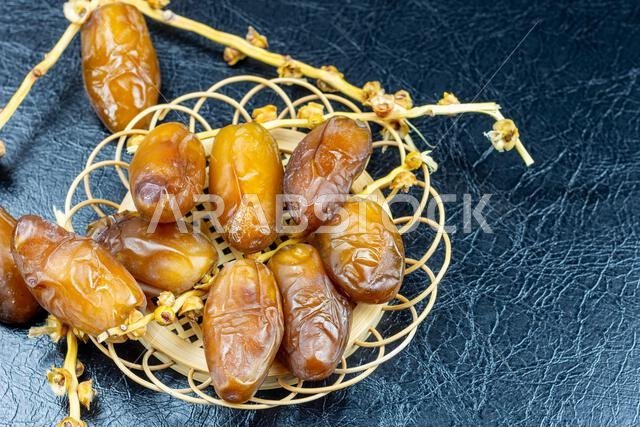 صورة مقرّبة لتمور جزائرية ملكية على طبق خشبي على خلفية سوداء. مفهوم رمضان.