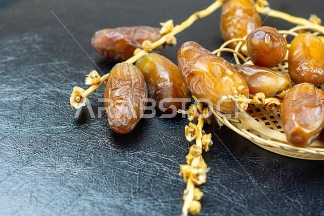 صورة مقرّبة لتمور جزائرية ملكية على طبق خشبي على خلفية سوداء. مفهوم رمضان.