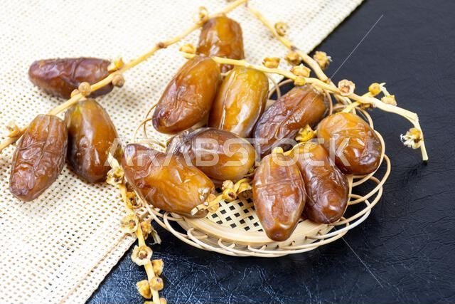 Close-up of Algerian royal dates on a wooden plate on a black background. Ramadan concept.