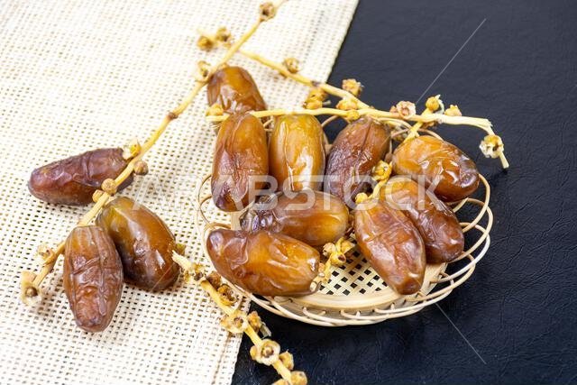 Close-up of Algerian royal dates on a wooden plate on a black background. Ramadan concept.