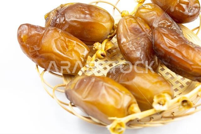 Close-up of Algerian royal dates on a wooden plate on a white background. Ramadan concept.