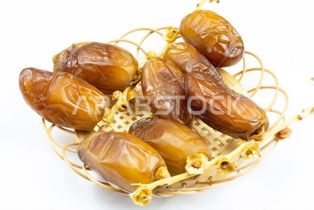 Close-up of Algerian royal dates on a wooden plate on a white background. Ramadan concept.