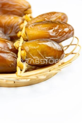 صورة مقرّبة لتمور جزائرية ملكية على طبق خشبي على خلفية بيضاء. مفهوم رمضان.