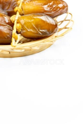 Close-up of Algerian royal dates on a wooden plate on a white background. Ramadan concept.