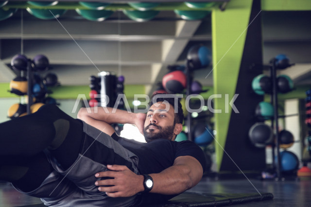 A Saudi Arabian Gulf youth doing exercises on a yoga mat, strengthening health and bodies, exercising in the gym