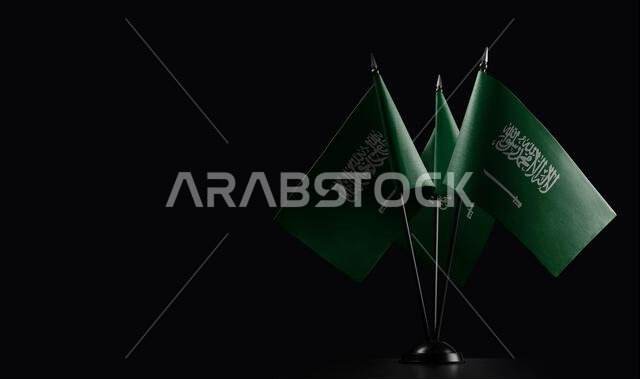 Small national flags of the Saudi Arabia on a black background