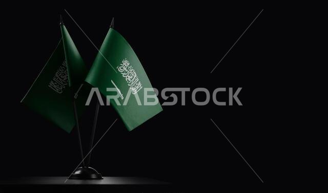 Small national flags of the Saudi Arabia on a black background