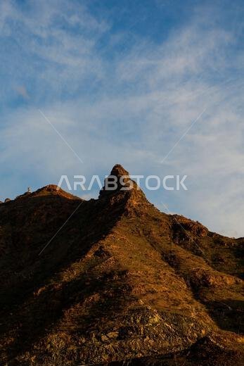 A vertical shot of the peak of a rocky mountain under blue sky  on a sunny day in Taif, Saudi Arabia