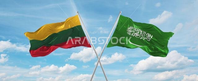 علمان متقاطعان، علم السعودية وعلم ليتوانيا، يرفرفان في مهب الريح تحت سماء ملبدة بالغيوم. يرمزان إلى العلاقة والحوار والسفر بين البلدين. رسم توضيحي ثلاثي الأبعاد