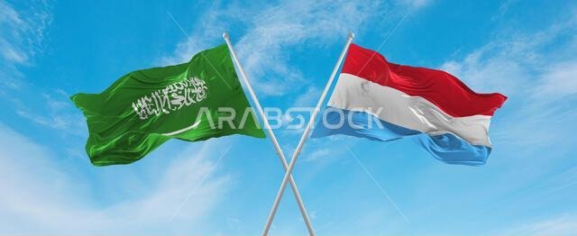 علمان متقاطعان، علم لوكسمبورغ وعلم السعودية، يرفرفان في مهب الريح تحت سماء ملبدة بالغيوم. يرمز هذا العمل الفني إلى مفهوم العلاقة والحوار والسفر بين البلدين. رسم ثلاثي الأبعاد