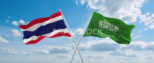 علمان متقاطعان، علم السعودية وعلم تايلاند، يرفرفان في مهب الريح تحت سماء ملبدة بالغيوم. يرمز هذا إلى مفهوم العلاقة والحوار والسفر بين البلدين. رسم توضيحي ثلاثي الأبعاد.