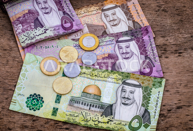 صورة لنقود معدنية وأوراق نقدية من فئة خمسة ريال سعودي من الإصدار الخامس عليها صورة خادم الحرمين الشريفين الملك عبد الله بن عبد العزيز آل سعود ، التمويل والاستثمار ، العملة الرسمية للمملكة العربية السعودية