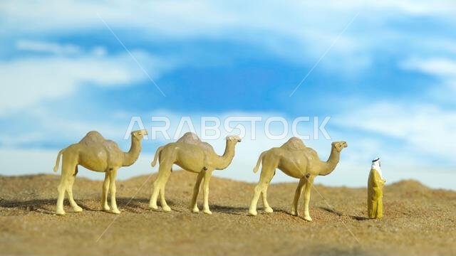 Miniature people toy figure photography. Middle eastern man wearing traditional clothes walking with camels in desert. Image photo Miniature people toy figure photography. Middle eastern man wearing traditional clothes walking with camels in desert. Image photo