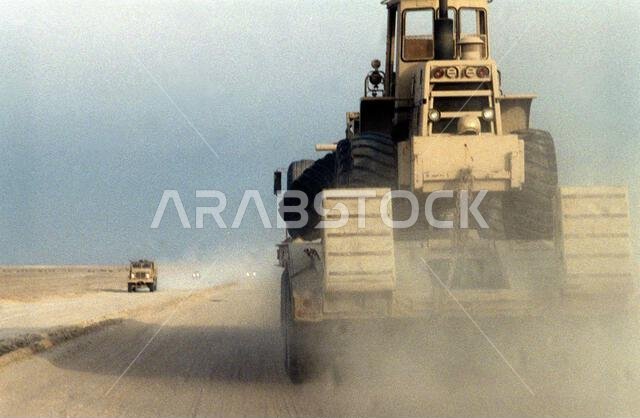 A road grader of Naval Mobile Construction Battalion 5 is transported by trailer along a main supply route during Operation Desert Storm. Exact Date Shot Unknown. Subject Operation/Series: DESERT STORM Country: Saudi Arabia (SAU)