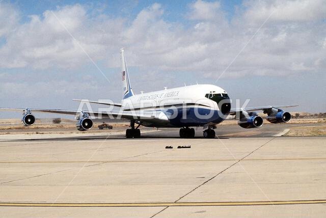 طائرة من طراز VC-137 ستراتولاينر تقف على مدرج المطار بعد نقلها وزير الدفاع ريتشارد تشيني والجنرال كولن باول، رئيس هيئة الأركان المشتركة، إلى المنطقة لحضور مؤتمر حول التدخل العسكري الأمريكي ضد العراق خلال عملية عاصفة الصحراء. الموضوع: عملية عاصفة الصحراء، الدولة: المملكة العربية السعودية.