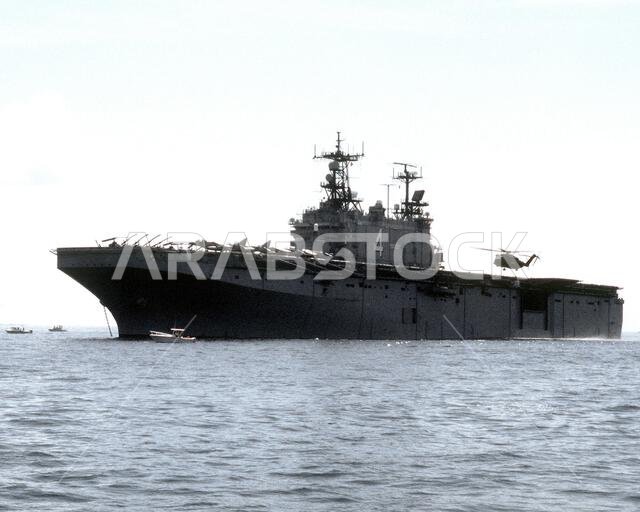 هبطت مروحية من طراز CH-53 Sea Stallion على متن سفينة الإنزال البرمائي USS NASSAU (LHA-4) الراسية قبالة الساحل. ستنقل NASSAU جنود مشاة البحرية الأمريكية ومعداتهم إلى المملكة العربية السعودية لدعم عملية درع الصحراء. العملية/السلسلة: درع الصحراء، الولاية: كارولاينا الشمالية، الدولة: الولايات المتحدة الأمريكية. هبطت مروحية من طراز CH-53 Sea Stallion على متن سفينة الإنزال البرمائي USS NASSAU (LHA-4) الراسية قبالة الساحل. ستنقل NASSAU جنود مشاة البحرية الأمريكية ومعداتهم إلى المملكة العربية السعودية لدعم عملية درع الصحراء. العملية/السلسلة: درع الصحراء، الولاية: كارولاينا الشمالية، الدولة: الولايات المتحدة الأمريكية.