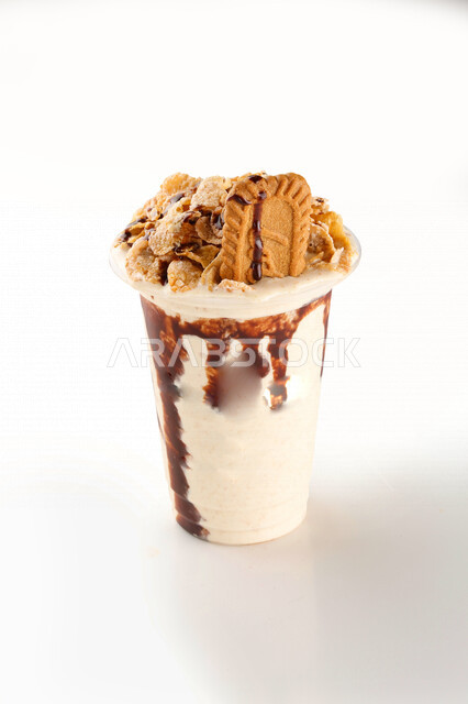 صورة مقربة لكوب من مشروب الميلك شيك، مشروبات باردة طازجة، مشروب ميلك شيك اللذيذ، الكريمة والبسكويت، الحلويات والسكريات، خلفية بيضاء