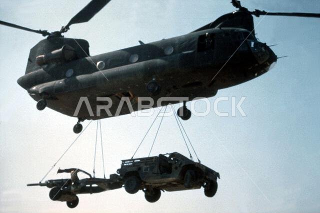 A CH-47 Chinook helicopter lifts an M102 105mm towed howitzer and an M998 High-Mobility Multipurpose Wheeled Vehicle (HMMWV) from a staging area where the equipment was part of a range demonstration for Saudi Arabian national guardsmen. The demonstration was conducted by members of the 1ST Battalion, 325th Airborne Infantry Regiment, during Operation Desert Shield. Subject Operation/Series: DESERT SHIELD Country: Saudi Arabia(SAU)