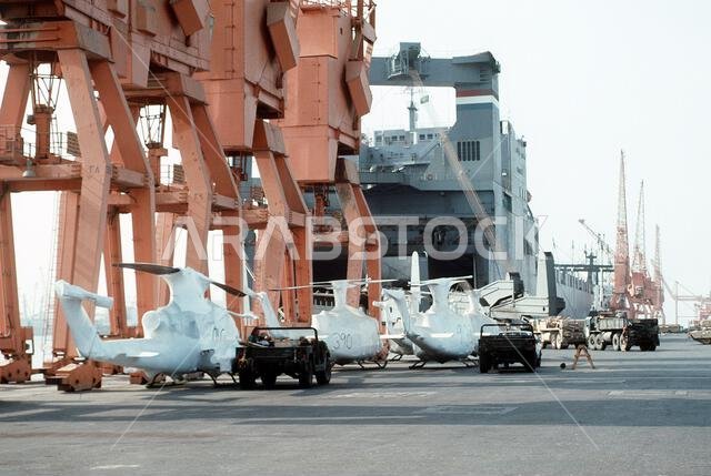 تقف مروحيات UH-1 إيروكوا ومروحيات AH-1 كوبرا الهجومية، المغطاة بأغطية واقية، على سطح سفينة شحن تابعة لقيادة النقل البحري العسكري، استعدادًا لإعادة نشرها في الولايات المتحدة في أعقاب عملية عاصفة الصحراء. الموضوع: عملية عاصفة الصحراء، الدولة: المملكة العربية السعودية.