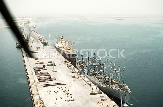 ترسو سفينة الشحن "كيب بون" (T-AK-5059)، المستأجرة من قبل قيادة النقل البحري العسكري، على رصيف الميناء مع فتح عنابر الشحن. ستحمل السفينة معدات وذخائر لإعادة نشرها في الولايات المتحدة في أعقاب عملية عاصفة الصحراء. ترسو سفينة تجارية خلف "كيب بون". العملية/السلسلة: عاصفة الصحراء. القاعدة: سفينة الشحن "كيب بون". الدولة: المملكة العربية السعودية.