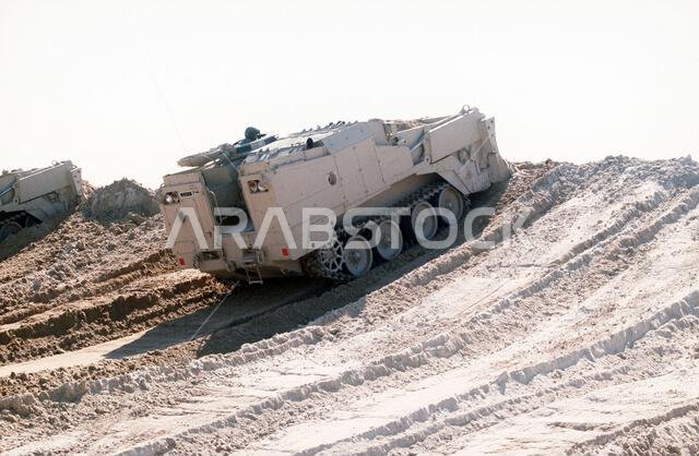قامت رافعتان مدرعتان من طراز M-9 تابعتان لقوة المشاة البحرية الثانية بتسوية ساتر ترابي على الحدود الكويتية مع بداية المرحلة البرية من عملية عاصفة الصحراء. العملية/السلسلة: عاصفة الصحراء، الدولة: المملكة العربية السعودية.