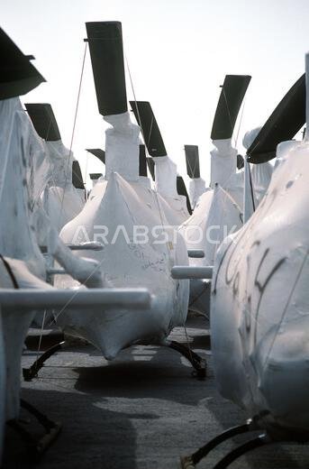 Military helicopters are wrapped for transport as they line a pier in preparation for loading aboard Military Sealift Command vehicle cargo ships. The helicopters will be redeployed to the United States in the aftermath of Operation Desert Storm. Subject Operation/Series: DESERT STORM Base: Ad Damman Country: Saudi Arabia (SAU)