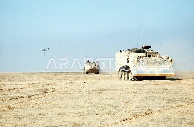 تتحرك جرافة قتالية مدرعة من طراز M-9 (ACE) ومركبة هجومية برمائية من طراز AAVP-7A1 تابعتان لقوة المشاة البحرية الثانية باتجاه الحدود الكويتية مع بدء المرحلة البرية من عملية عاصفة الصحراء. العملية/السلسلة: عاصفة الصحراء، الدولة: المملكة العربية السعودية.